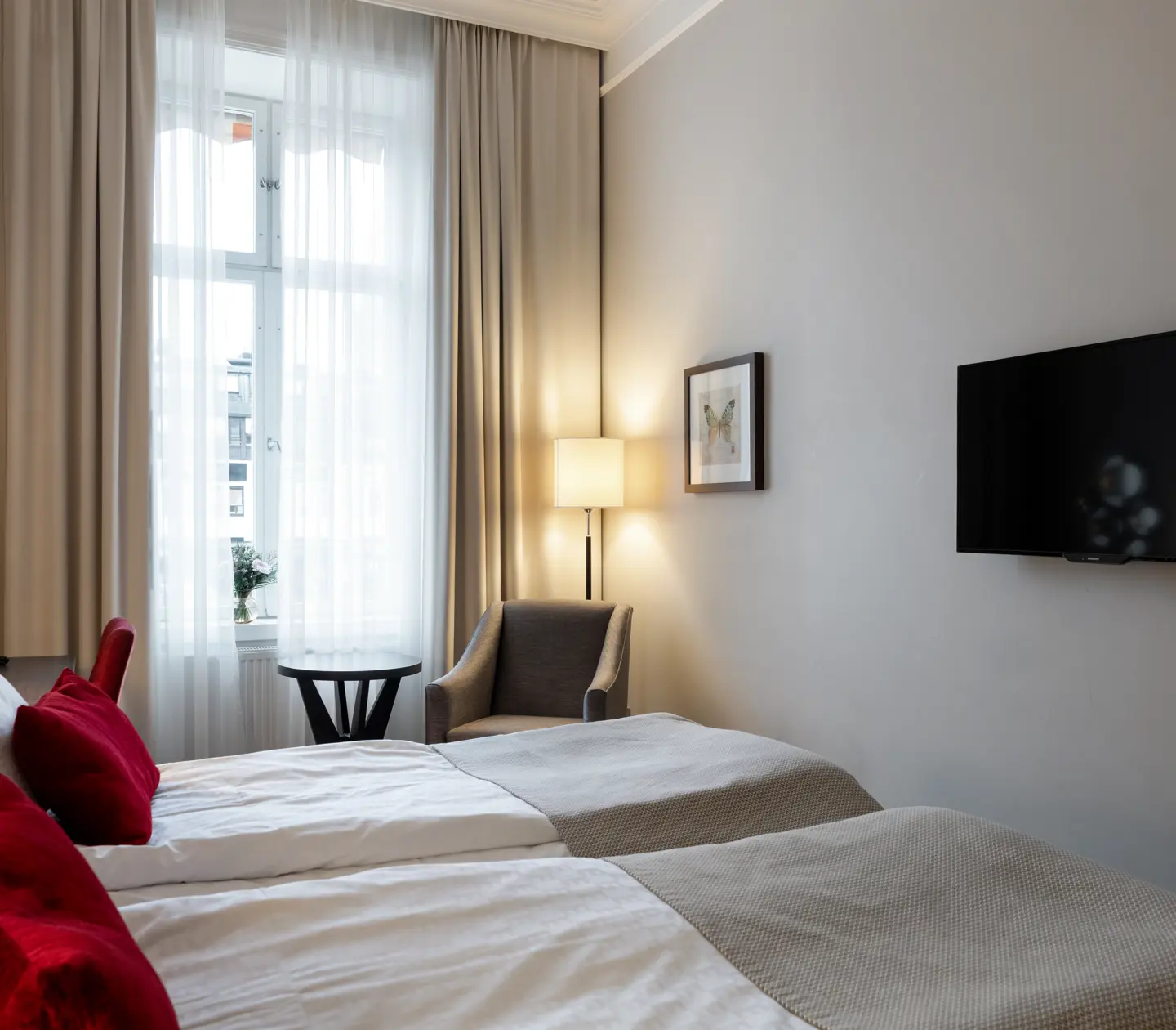 Hotellrum med dubbelsäng, tv och fåtölj