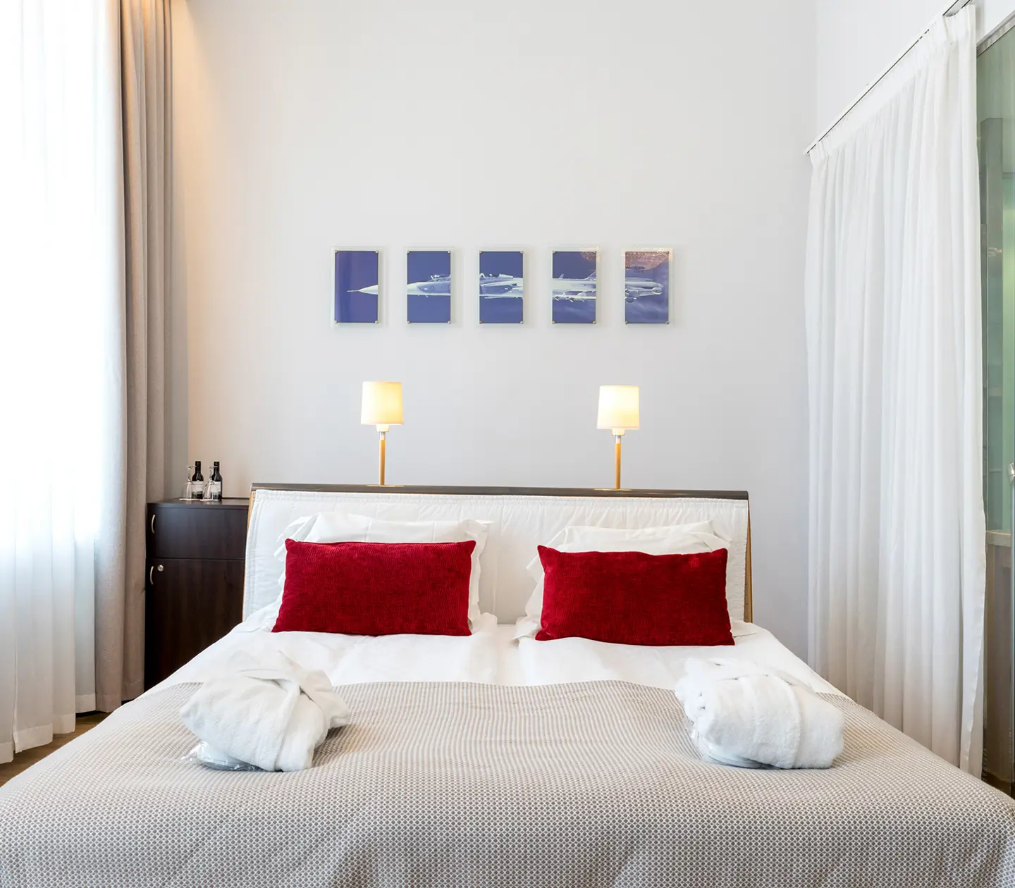Ljust hotellrum med säng, morgonrockar och tv