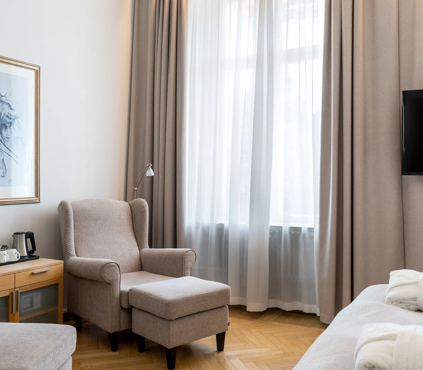 Ljust hotellrum med morgonrockar, fåtöljer och tv
