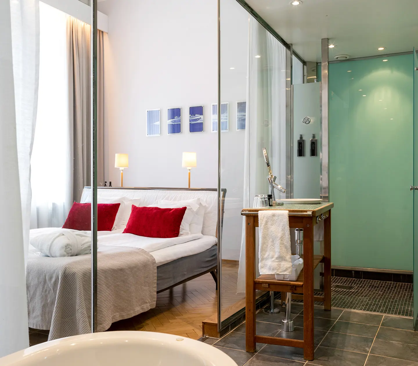Ljust hotellrum med badrum, glasvägg och hotellrum