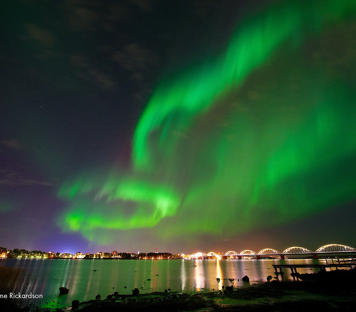 Norrsken över Luleå som speglar sig i vattnet