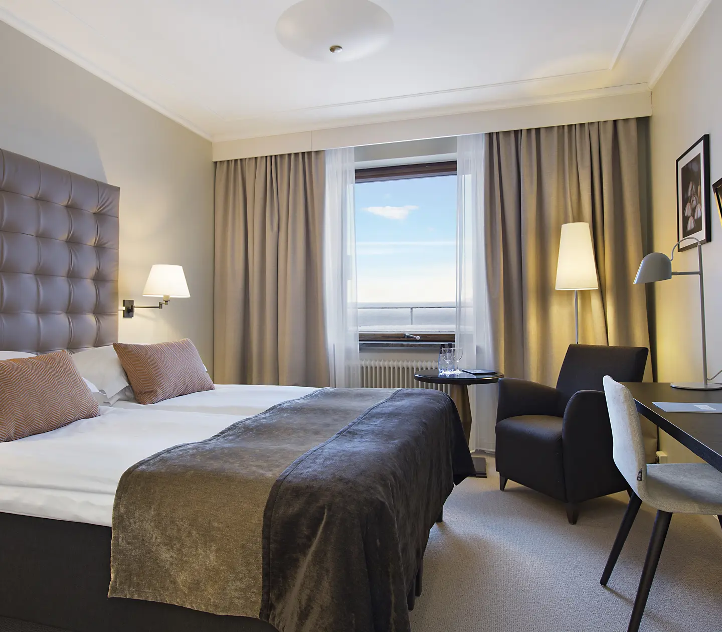 Hotellrum med dubbelsäng, skrivbord och fönster med havsutsikt