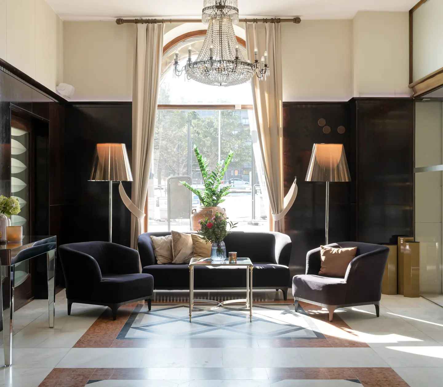 Hotellobby med sittgrupp, kristallkrona och stort fönster