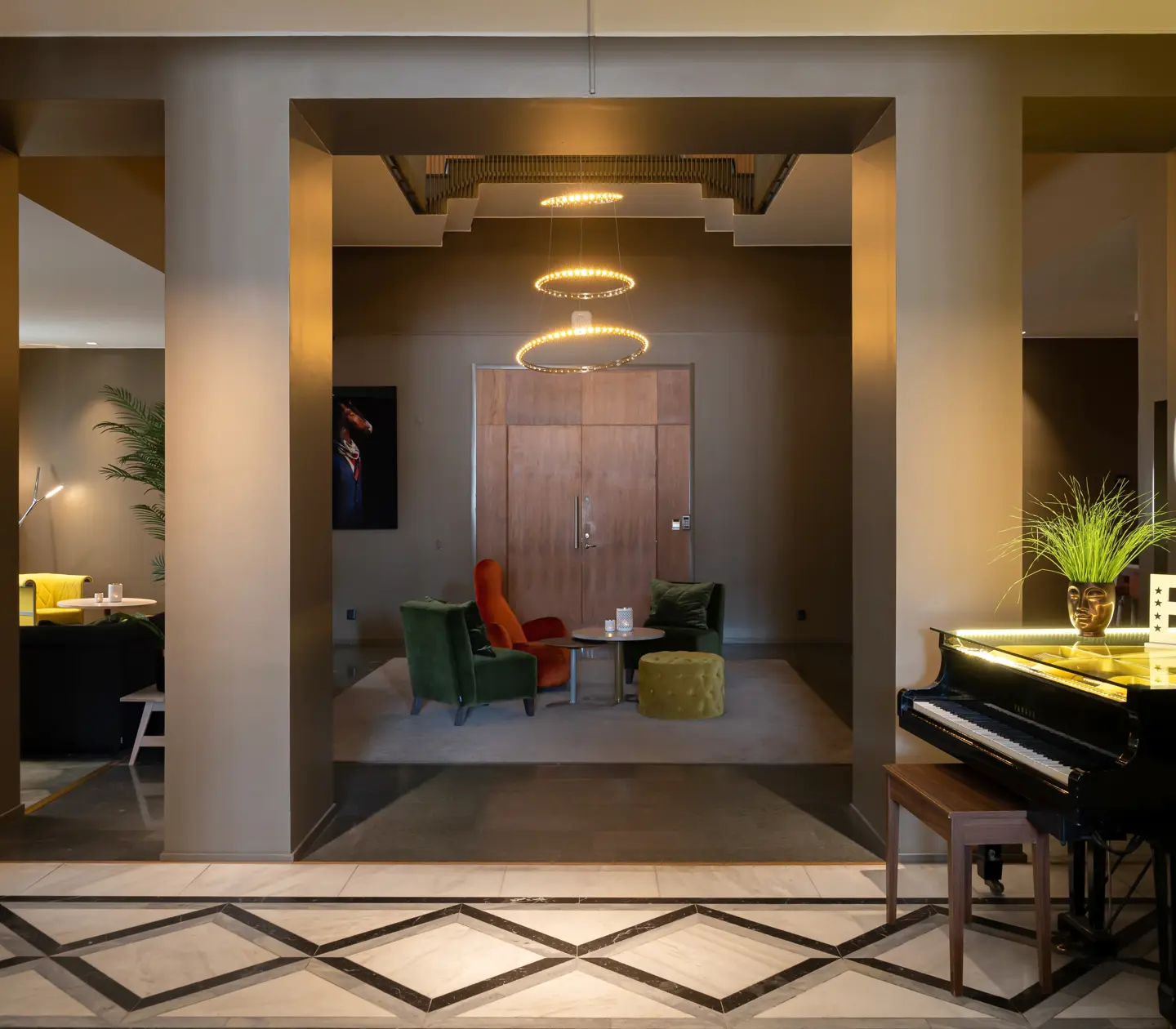 Hotellobby med sittgrupper, piano och stor lampa