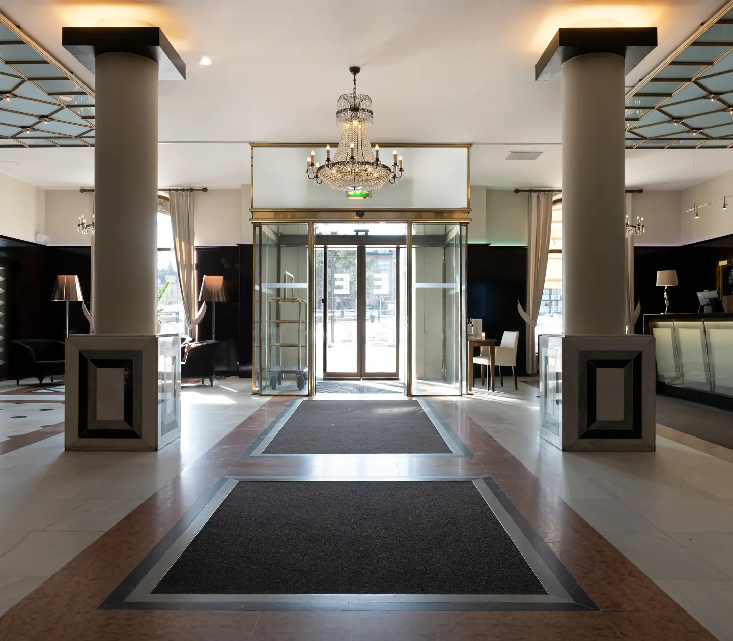 Hotellobby med receptionsdisk, kristallkrona och pelare