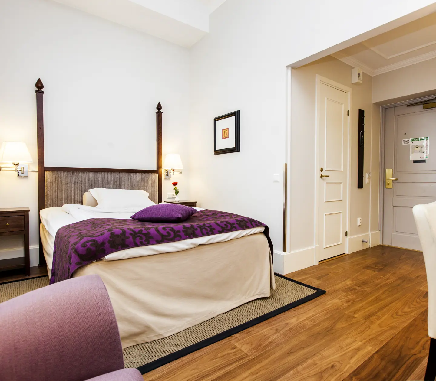 Ljust hotellrum med skrivbord, enkelsäng och tavla