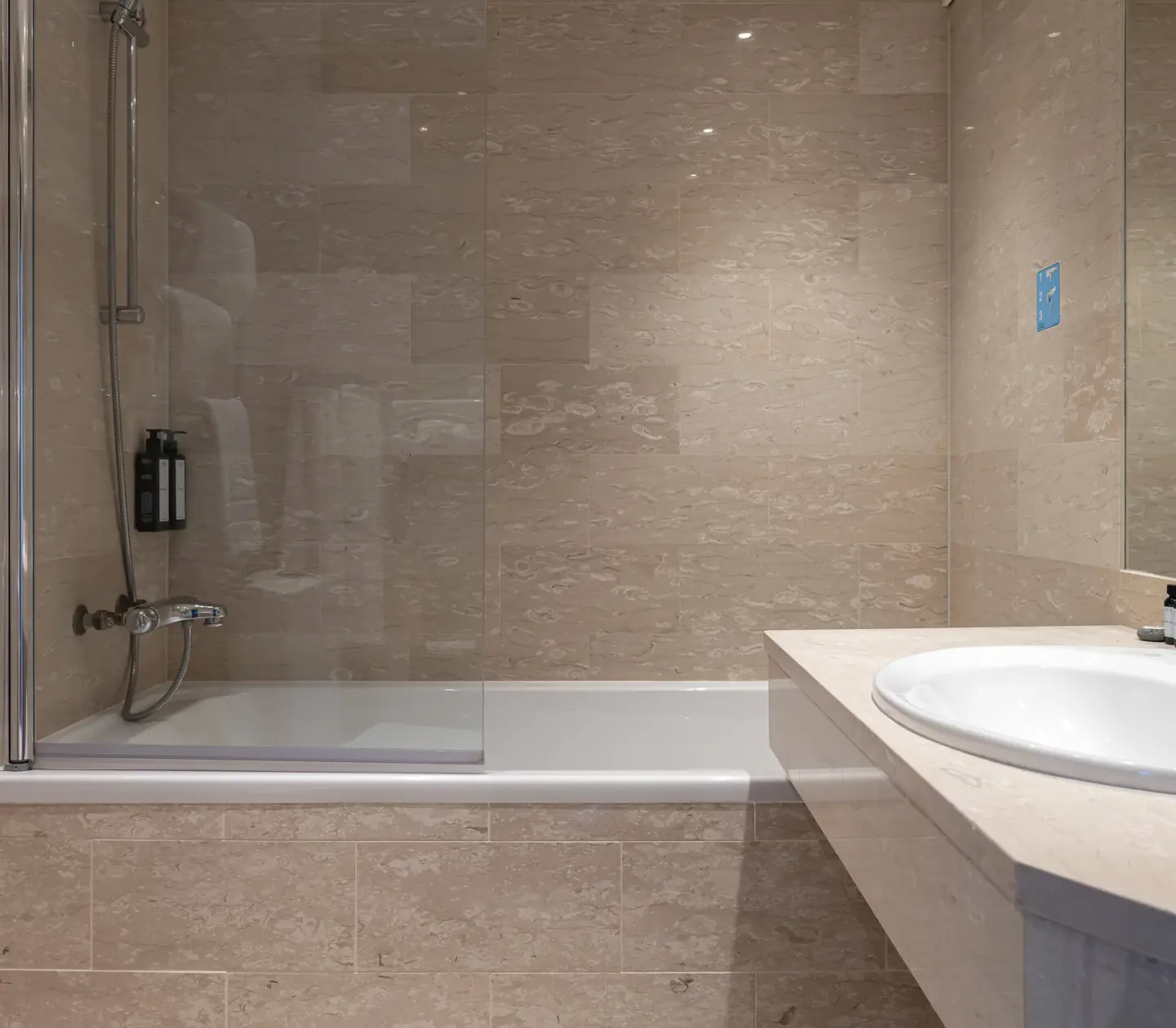 Beige badrum med handfat, badkar och spegel