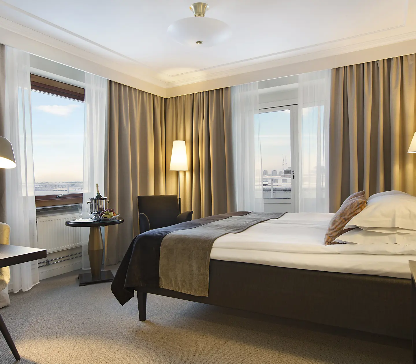 Ljust hotellrum med säng, fåtölj och fönster med havsutsikt