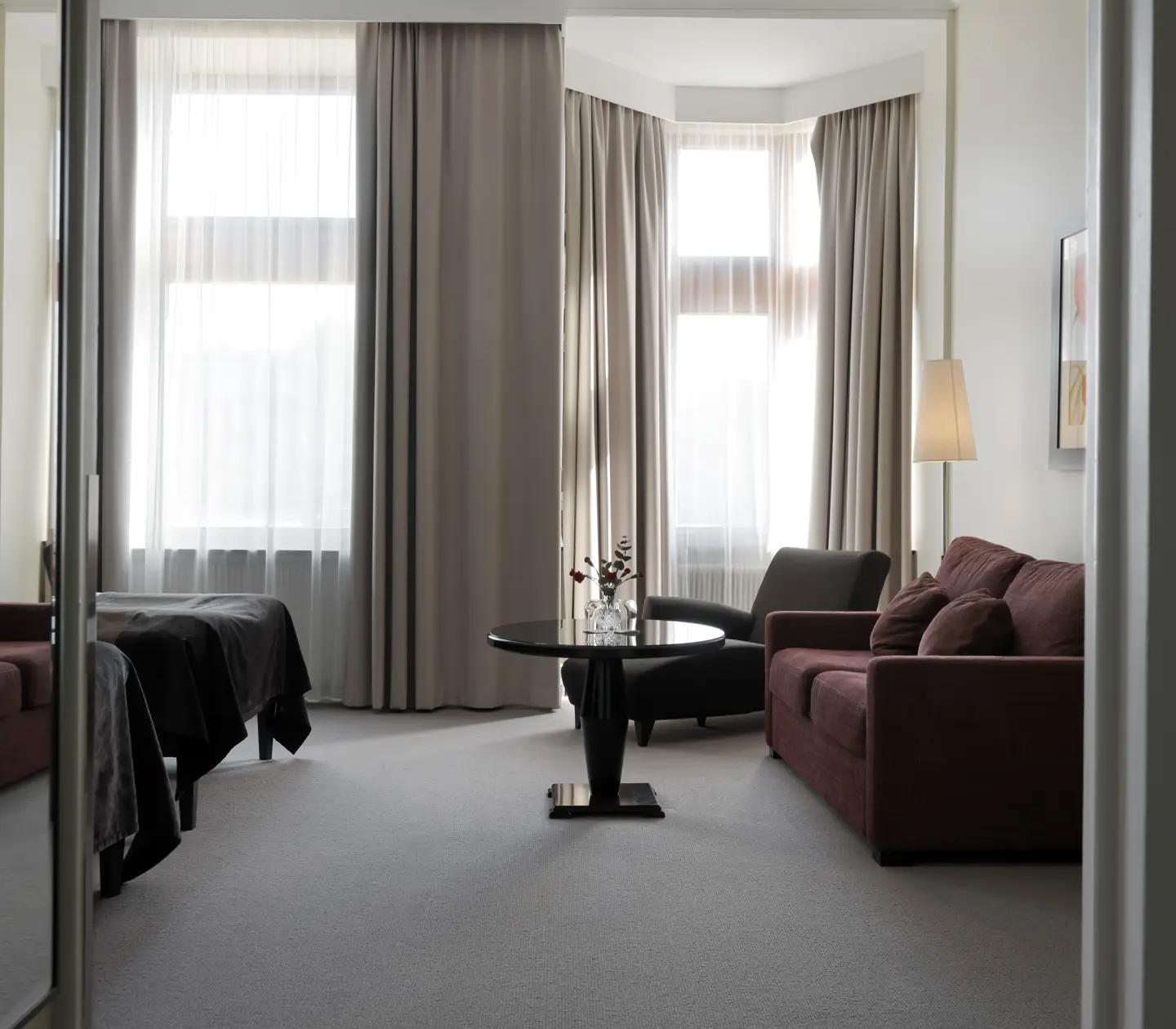 Ljust hotellrum med sittgrupp, fönster och spegel