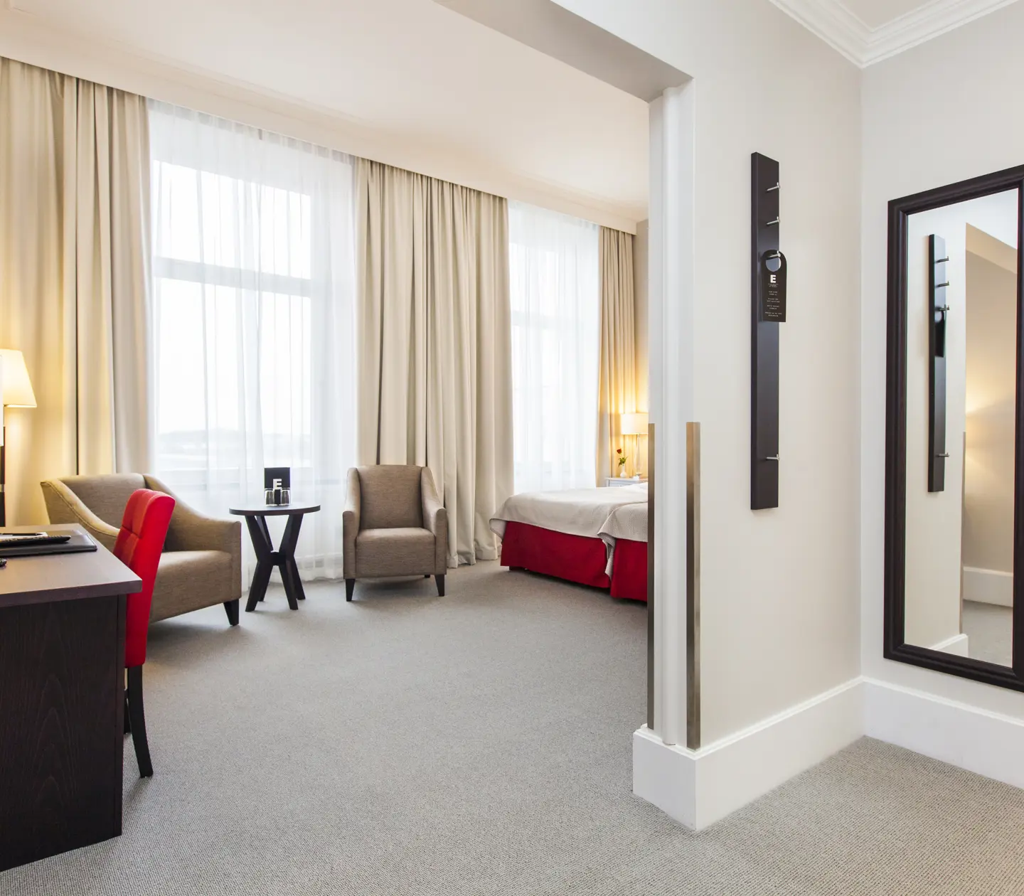 Ljust hotellrum med skrivbord, fåtöljer och fönster