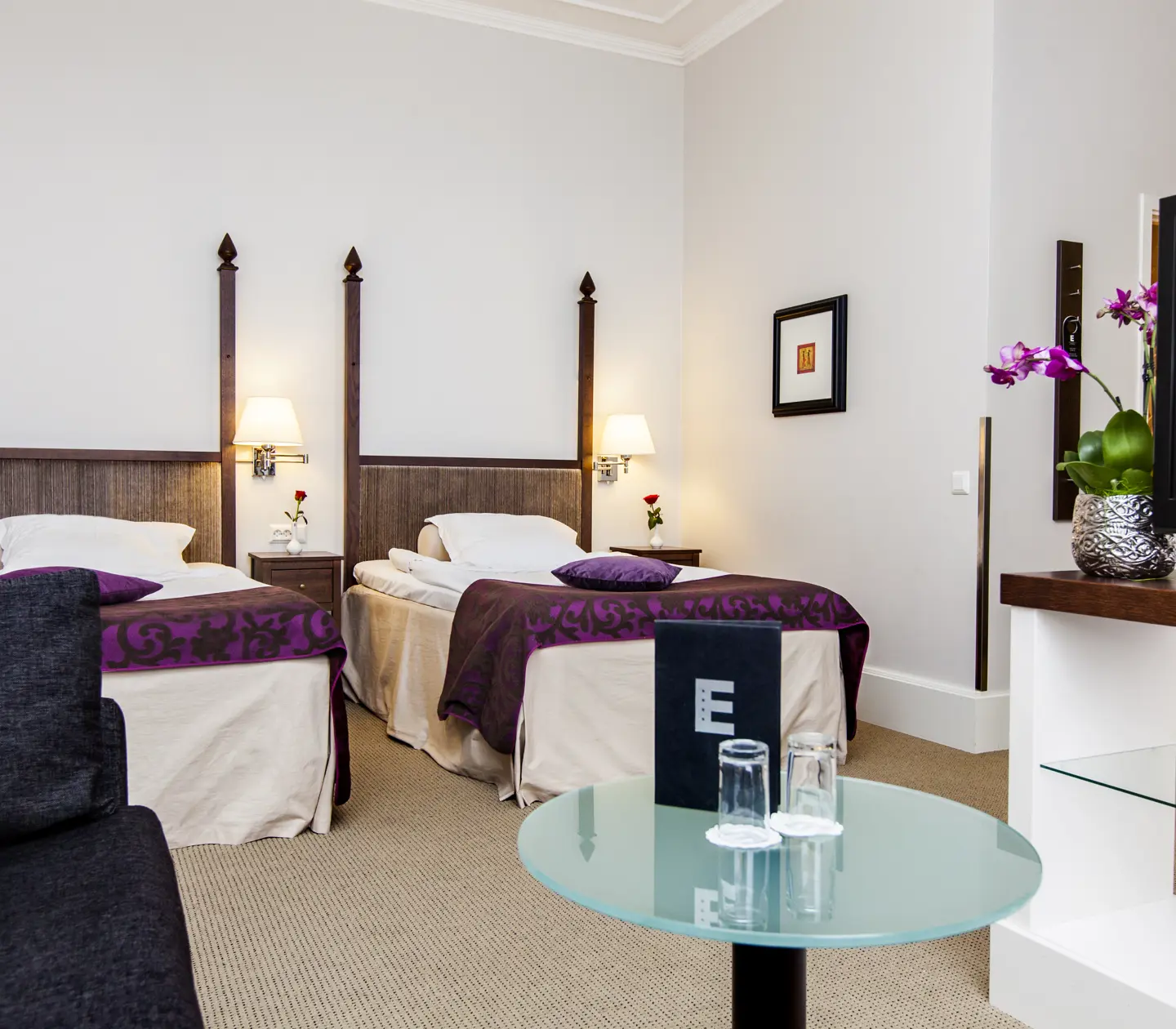 Ljust hotellrum med två sängar, sängbord och tv