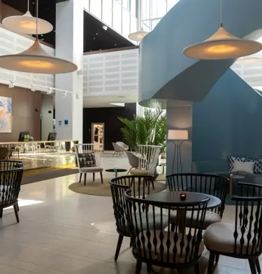 Hotellobby med receptionsdisk, många matplatser och blå trappa