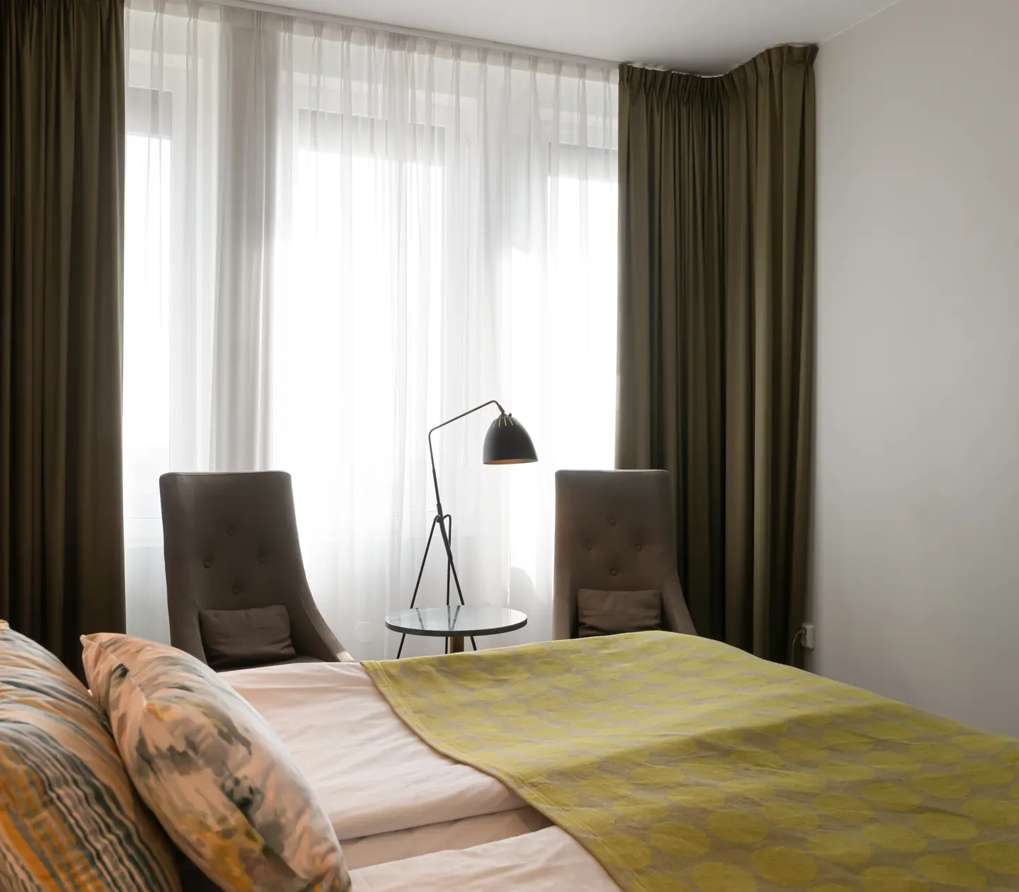 Hotellrum med säng, fåtölj och gardiner