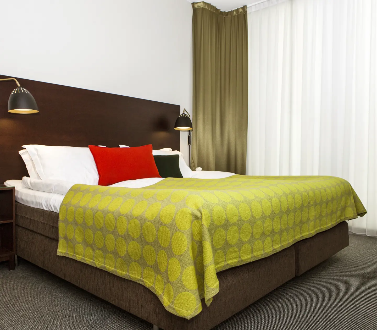 Hotellrum med säng, stor sänggavel och sänglampor
