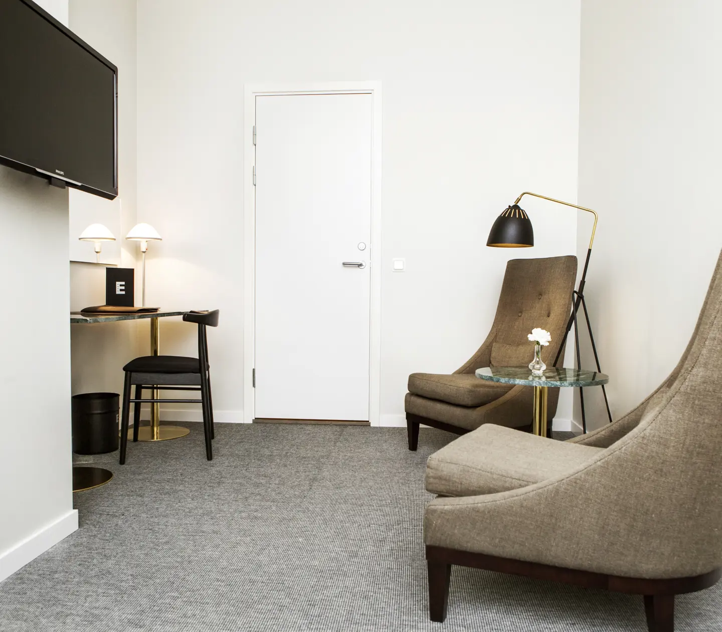 Hotellrum med skrivbord, fåtöljer och tv