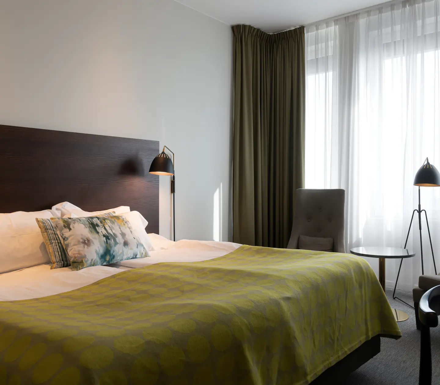 Ljust hotellrum med säng, fåtöljer och fönster