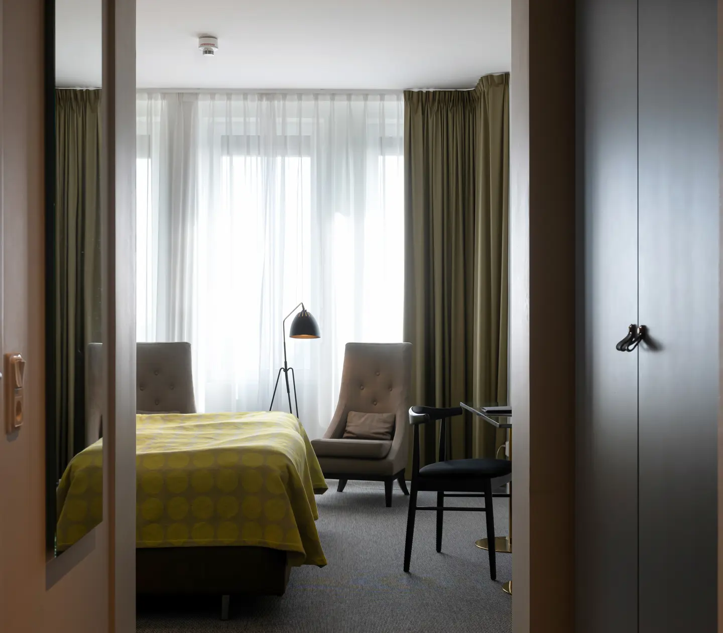 Hotellrum med säng, fåtölj och fönster