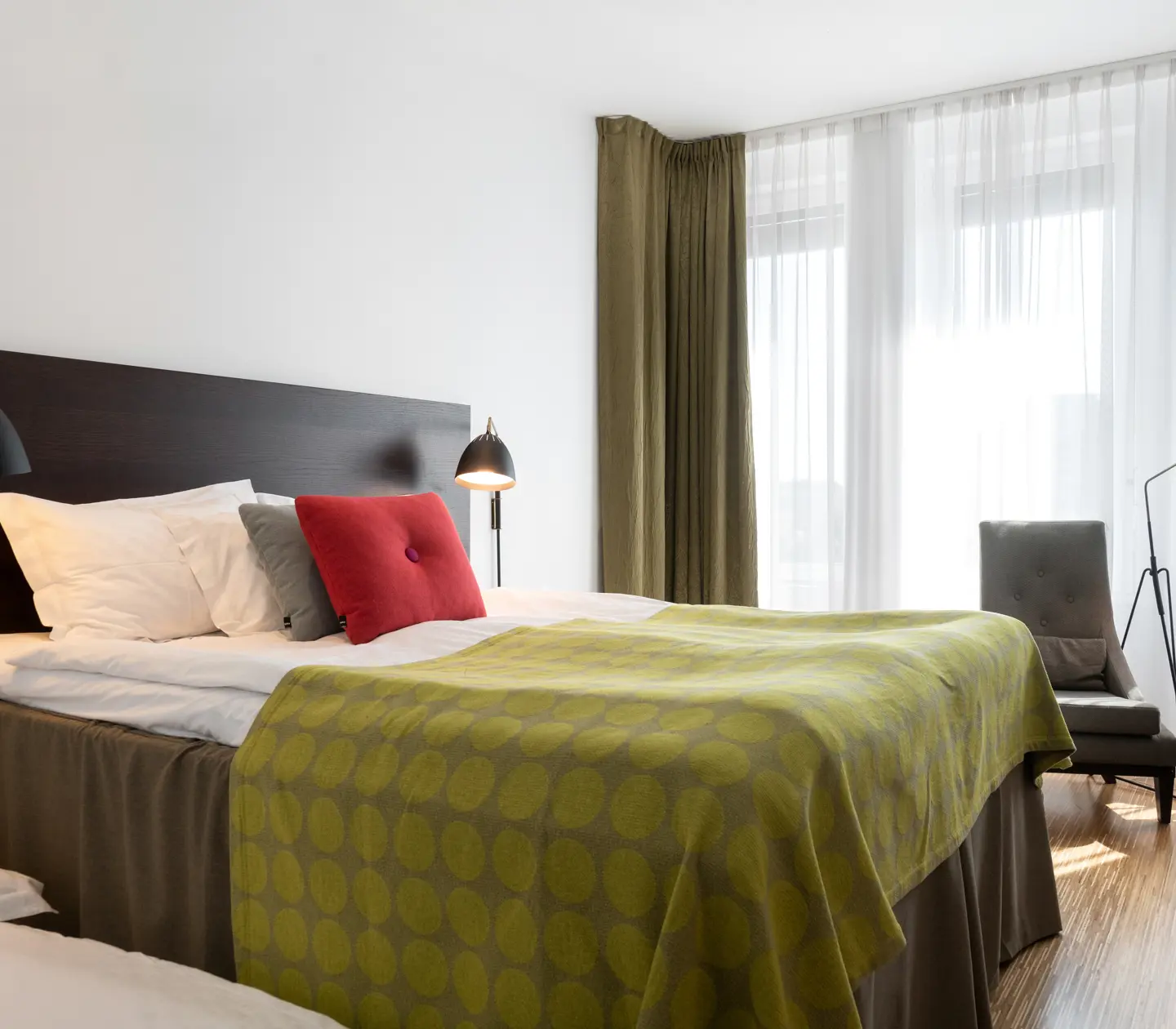 Ljust hotellrum med säng, fåtöljer och fönster