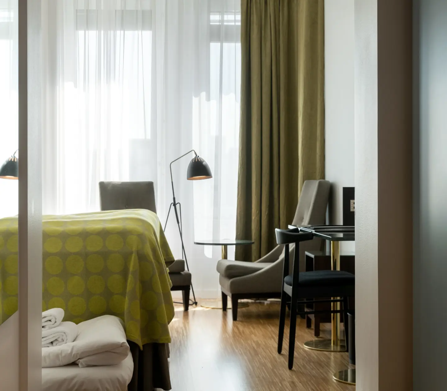 Hotellrum med säng, fåtöljer och fönster