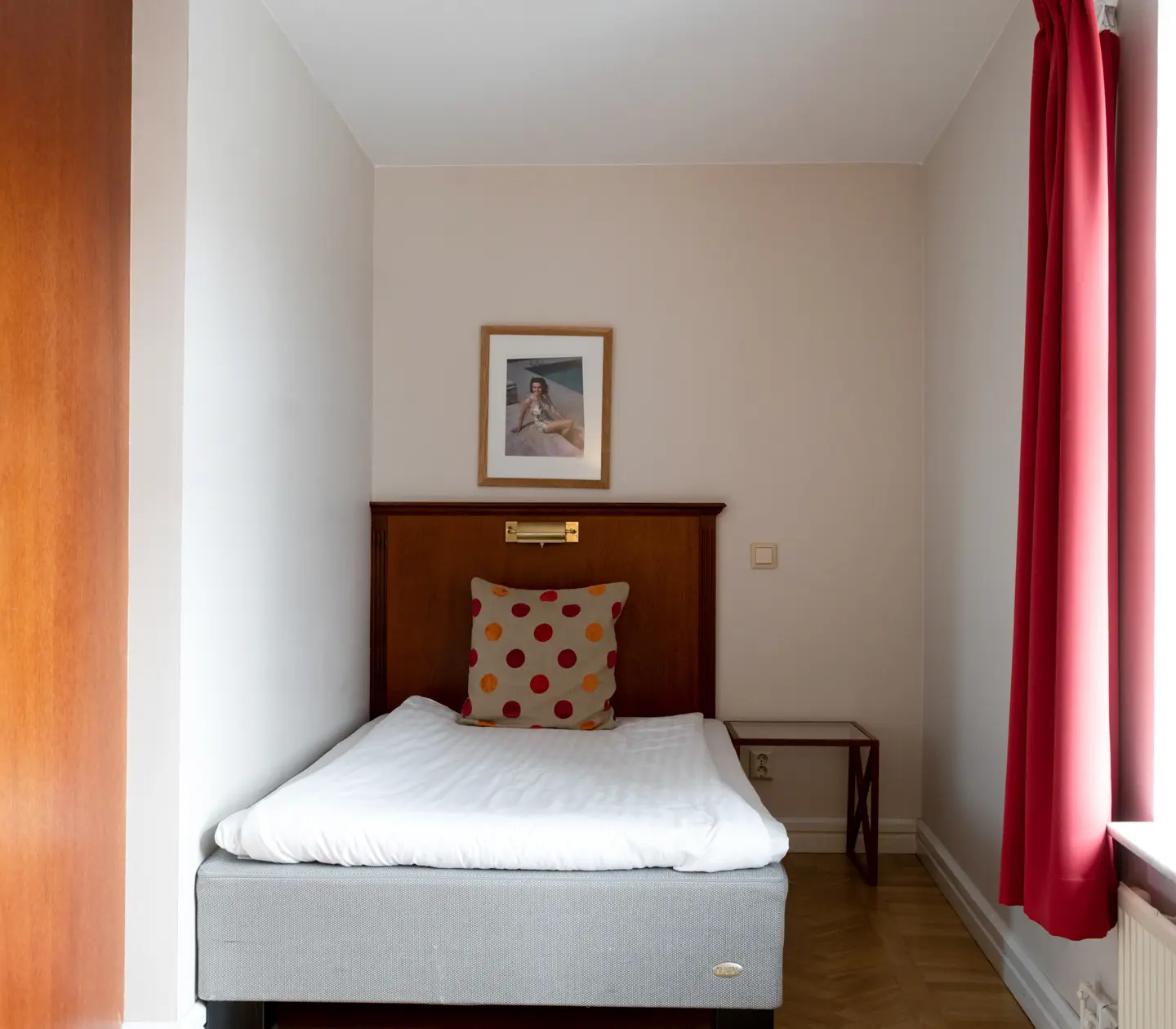 Hotellrum med säng, sänggavel i trä och fönster