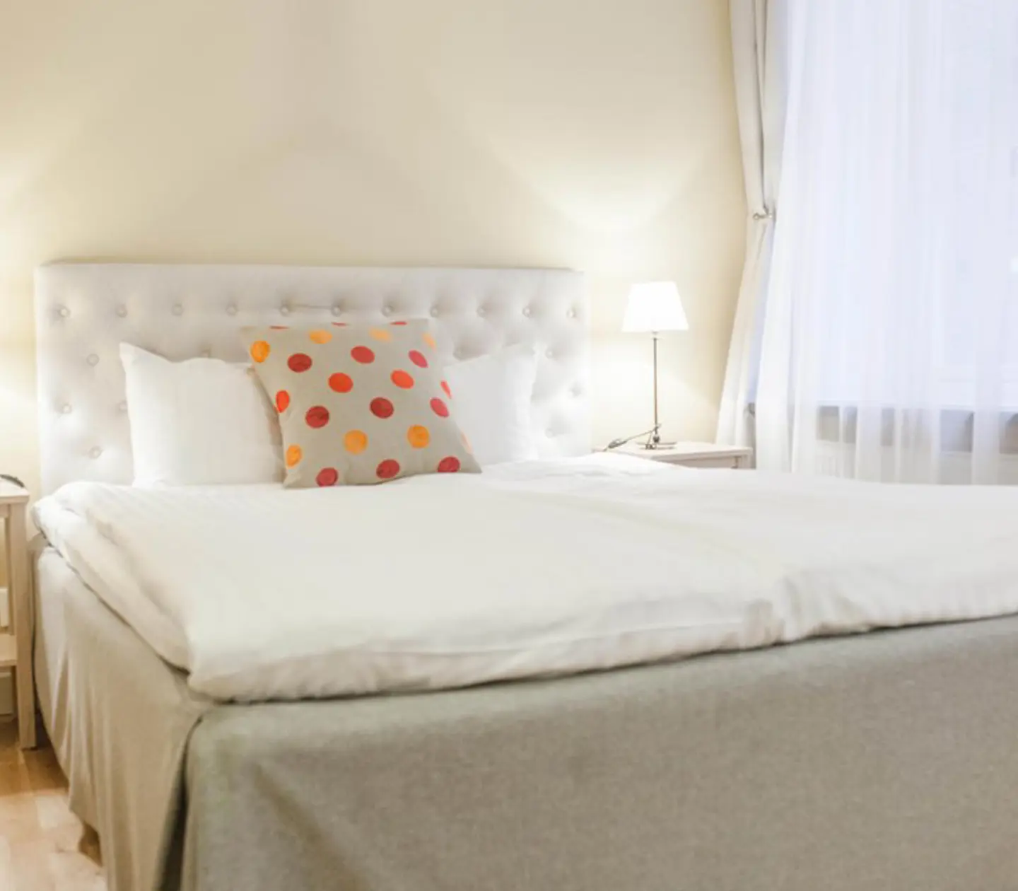 Hotellrum med säng, vit sänggavel och prickiga kuddar