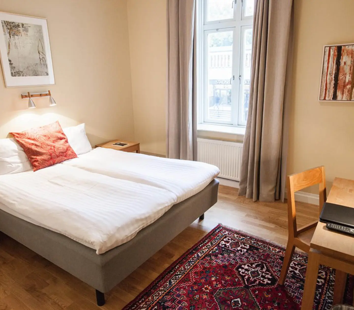 Mysigt hotellrum med säng, fönster och skrivbord
