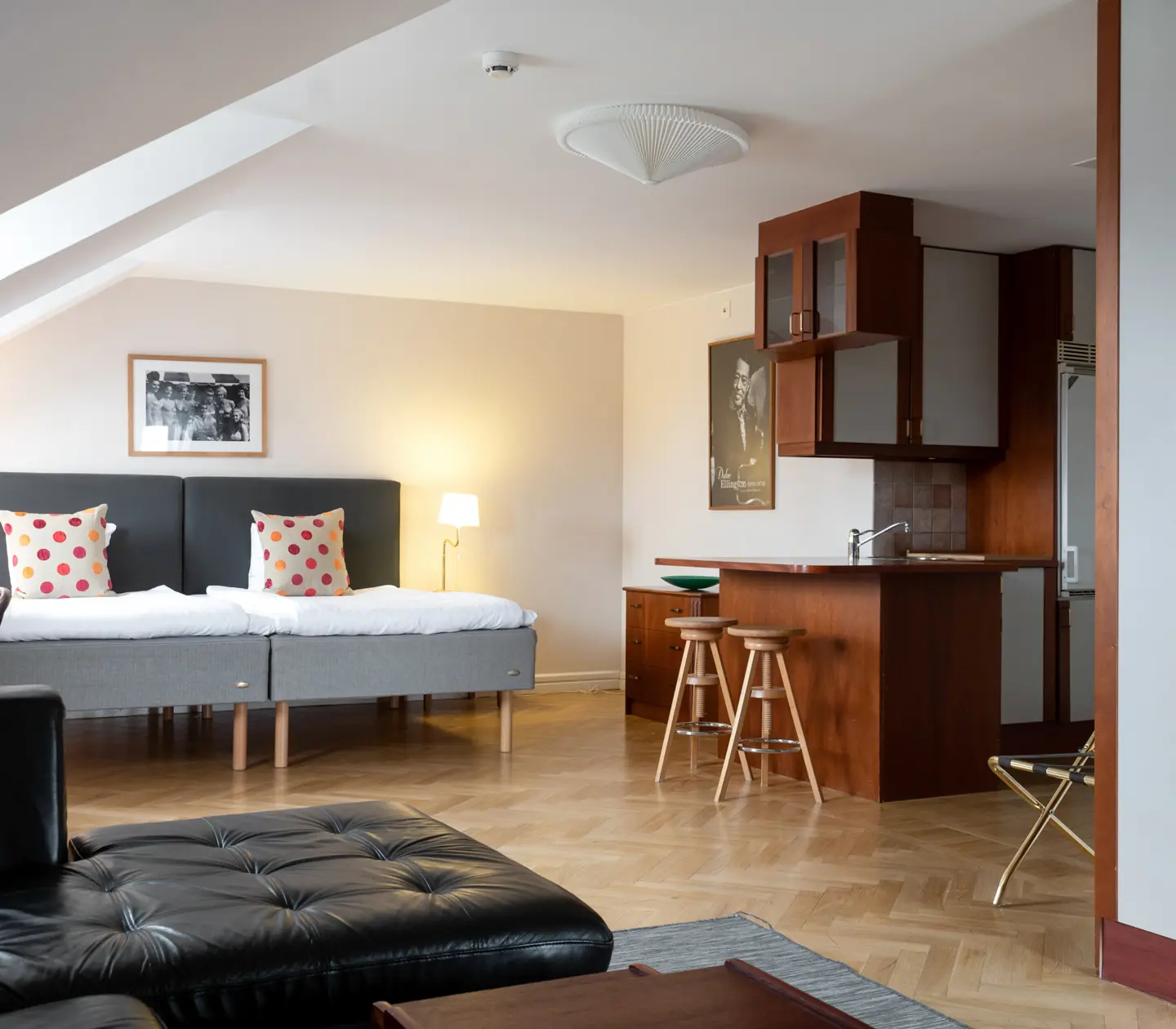 Hotellrum med sängar, svart soffa och kök