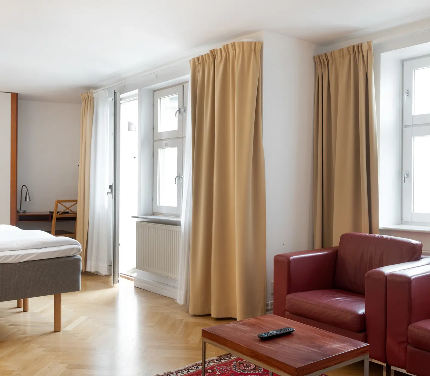 Ljust hotellrum med röda läderfåtöljer, fönster och garderob