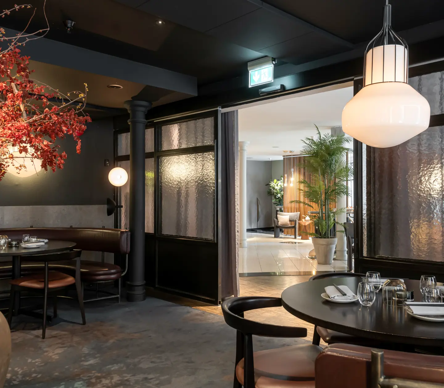 Restaurangmiljö med bord och rött stort träd