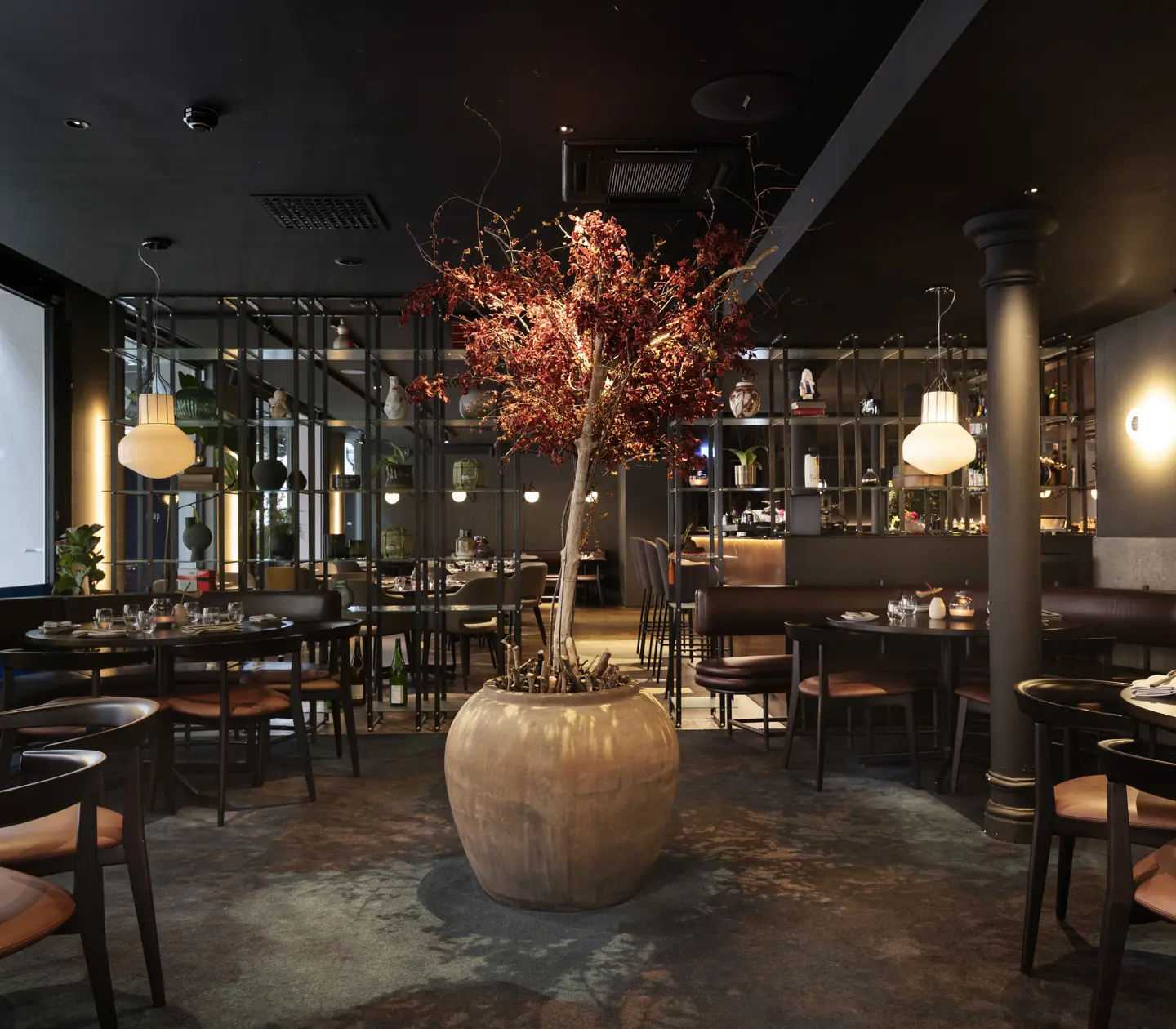Restaurangmiljö med stort rött träd i mitten