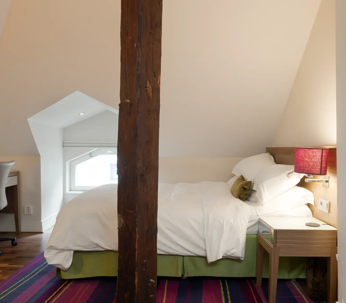 Hotellrum med snedtak, dubbelsäng och skrivbord