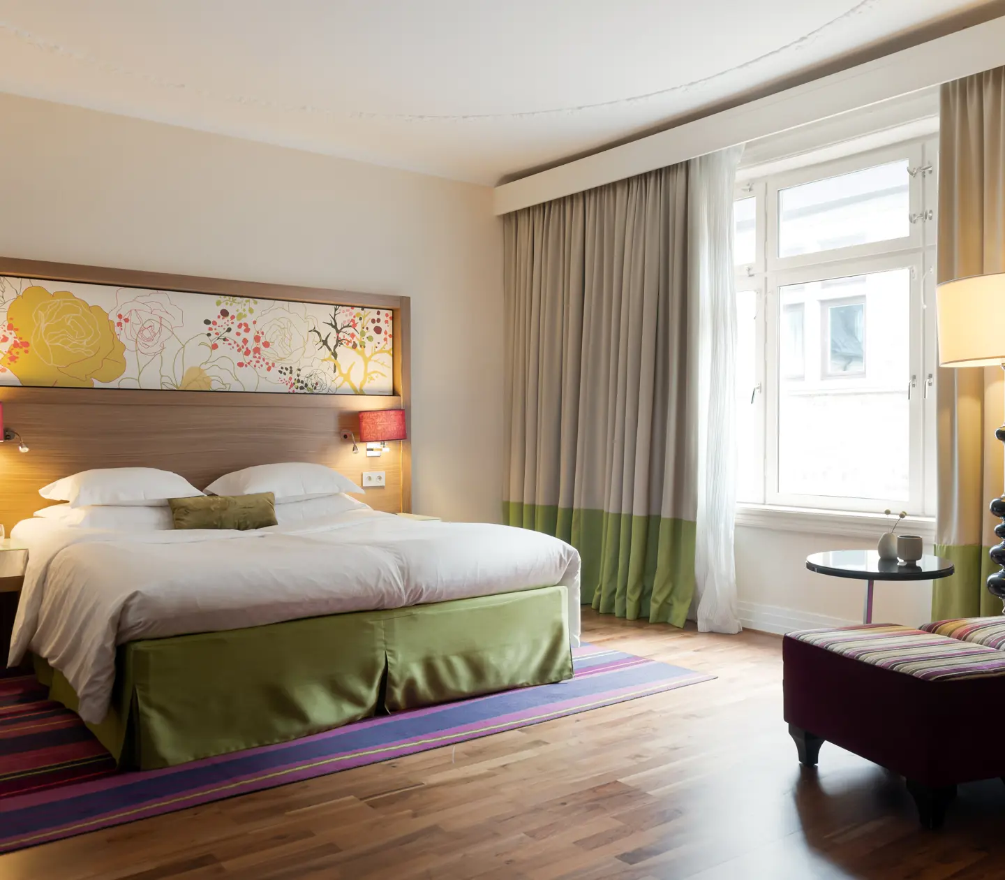 Stort hotellrum med dubbelsäng, fåtölj och fönster