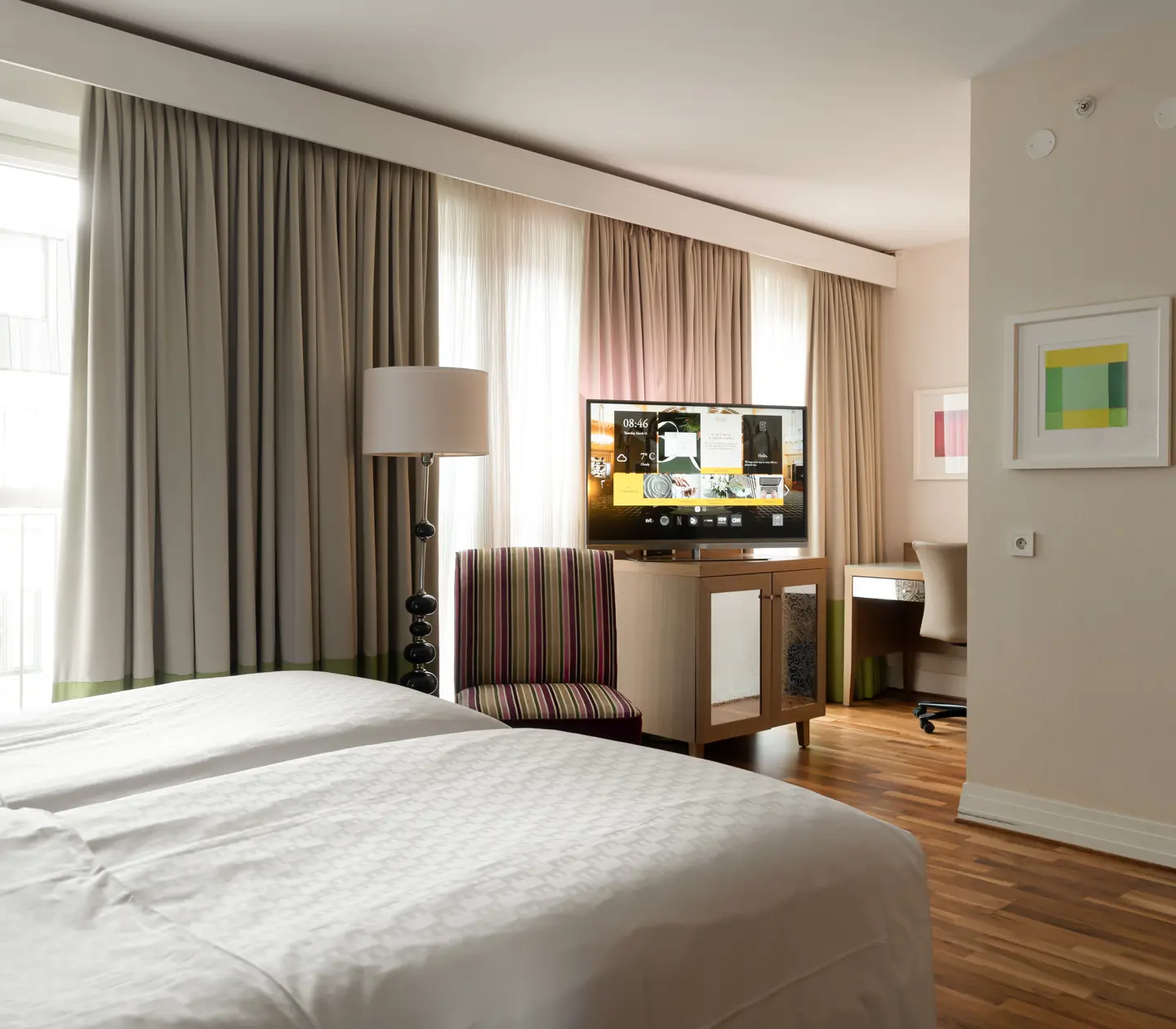 Hotellrum med tv, fåtölj och stora fönster
