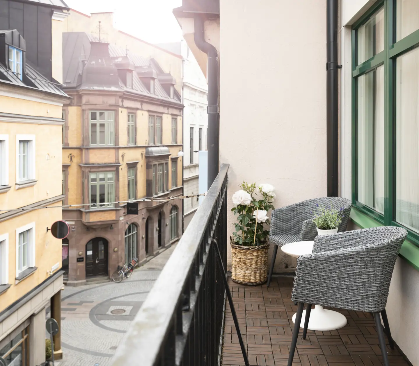 Balkong mot stadsgata med fåtöljer och blomma