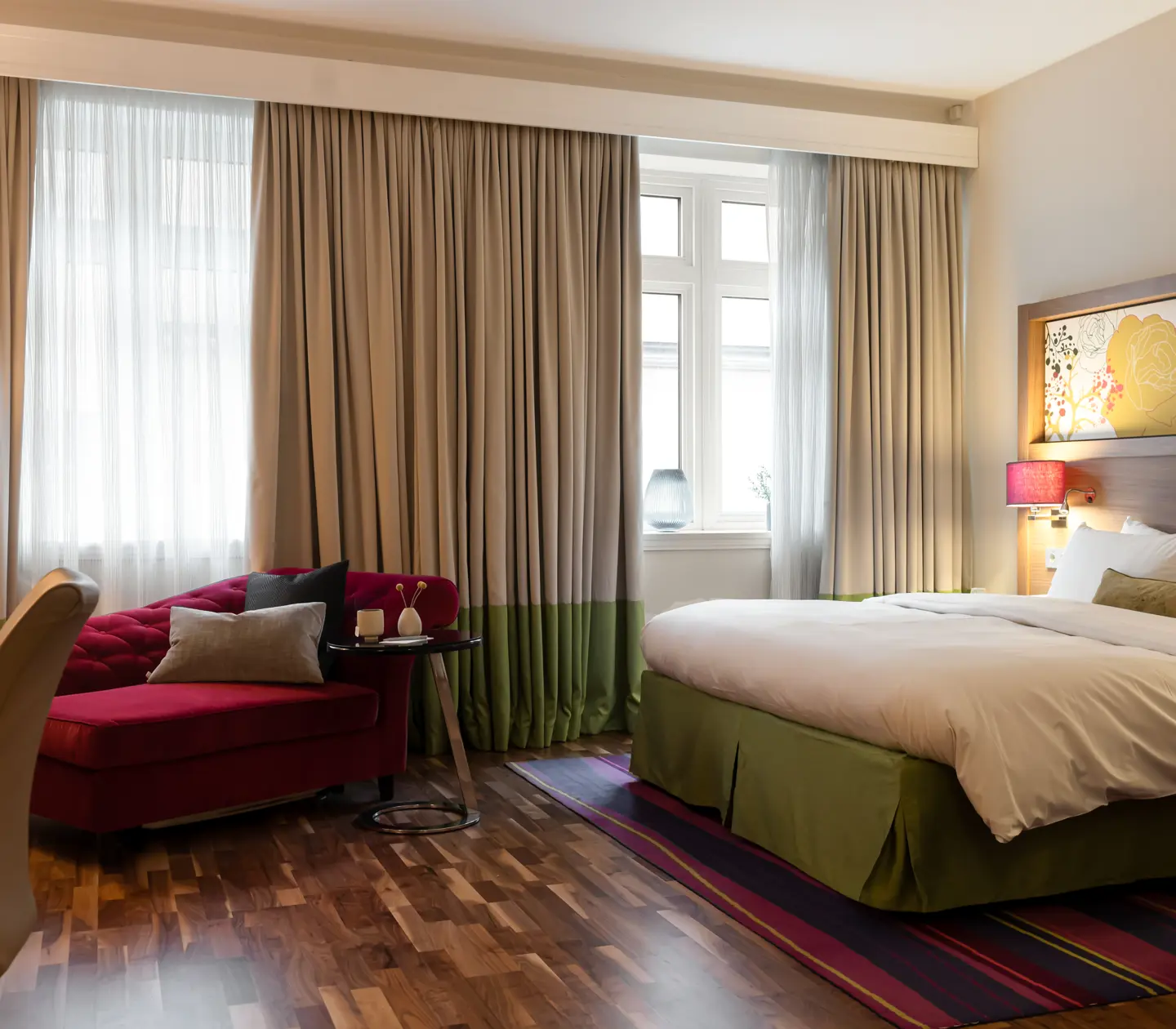 Hotellrum med dubbelsäng, fåtölj och stora fönster