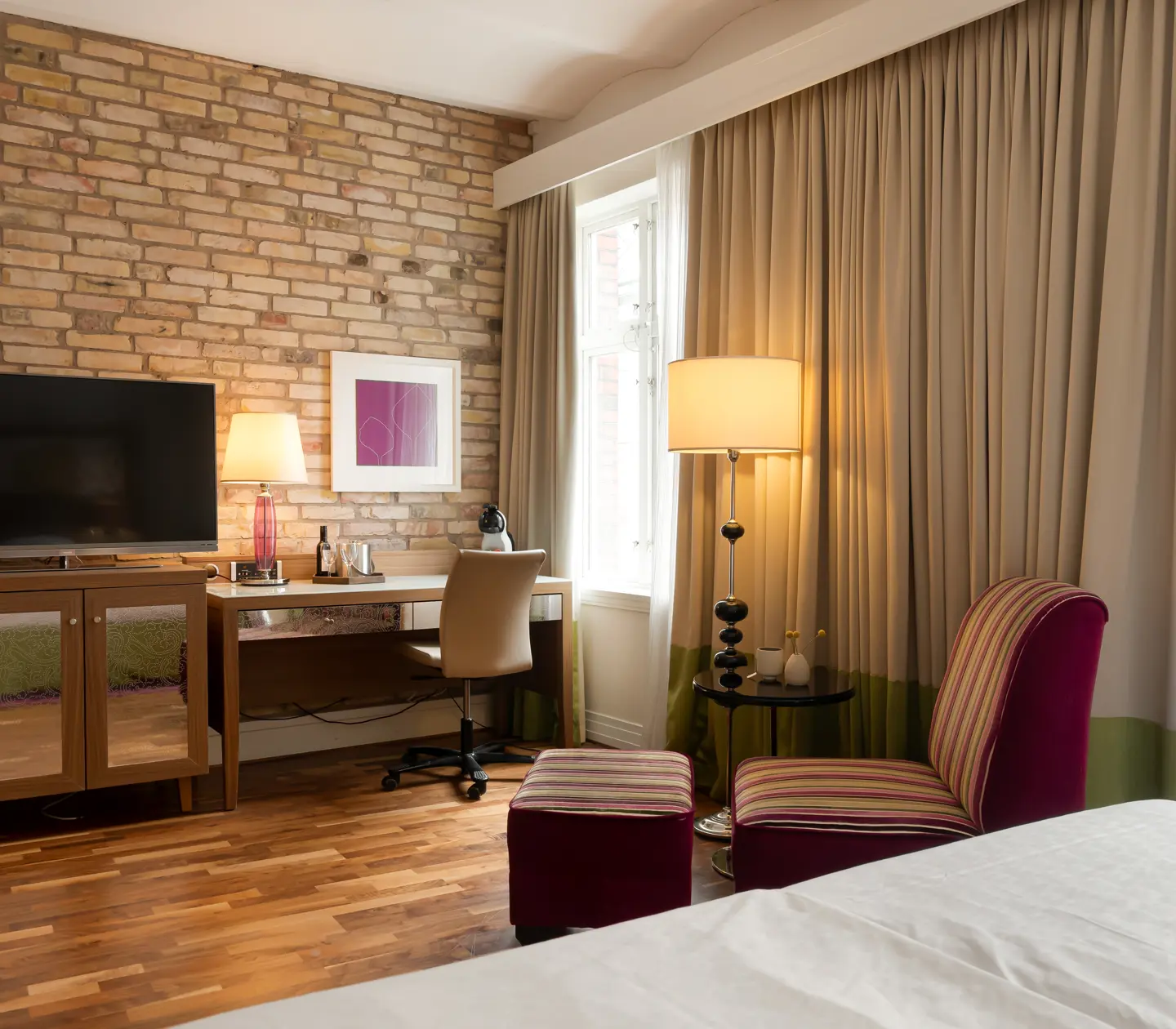 Hotellrum med tegelvägg, tv och fåtölj