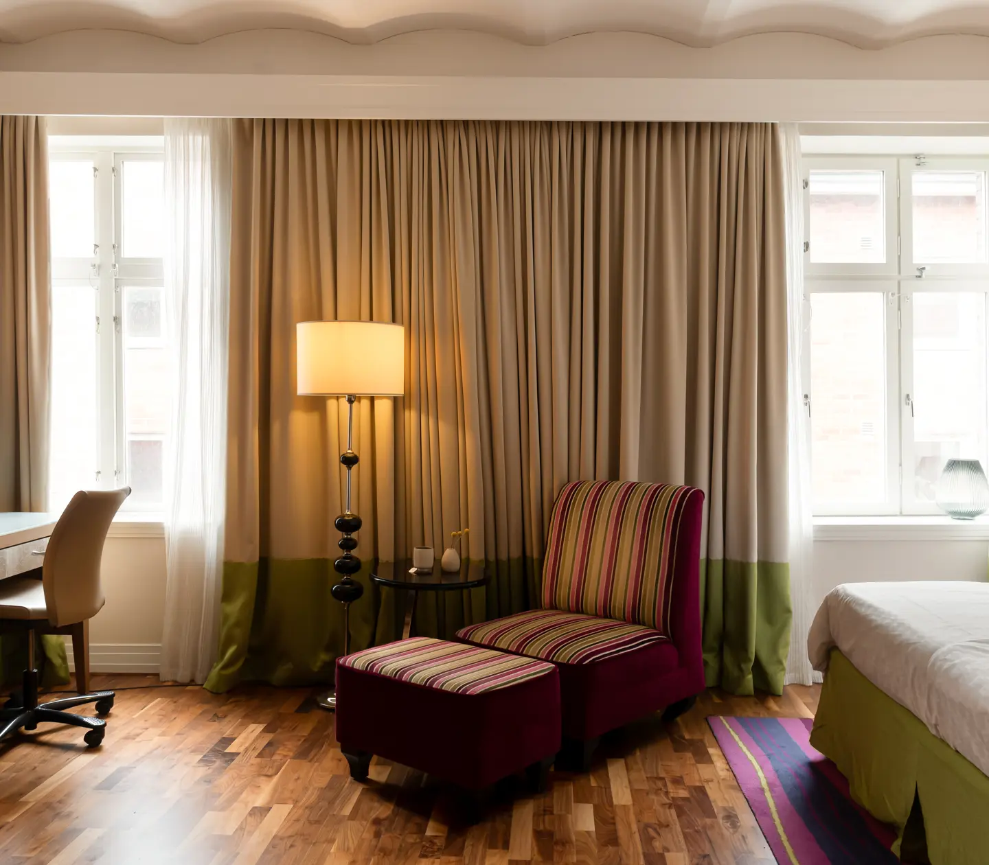 Hotellrum med fåtölj, skrivbord och fönster