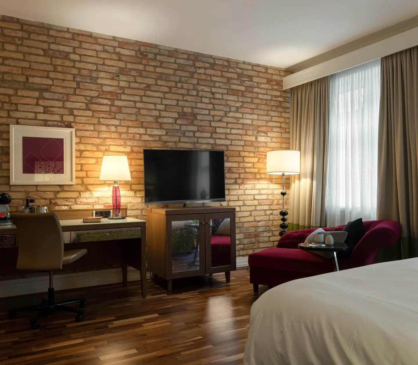 Hotellrum med tegelvägg, skrivbord och tv