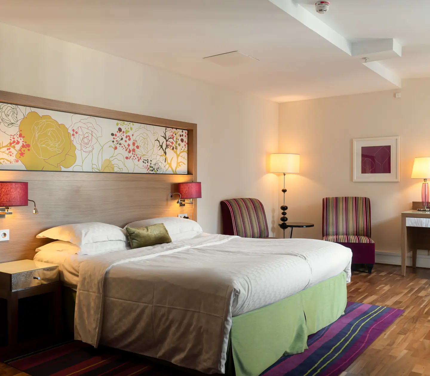 Hotellrum med dubbelsäng, fåtöljer och skrivbord