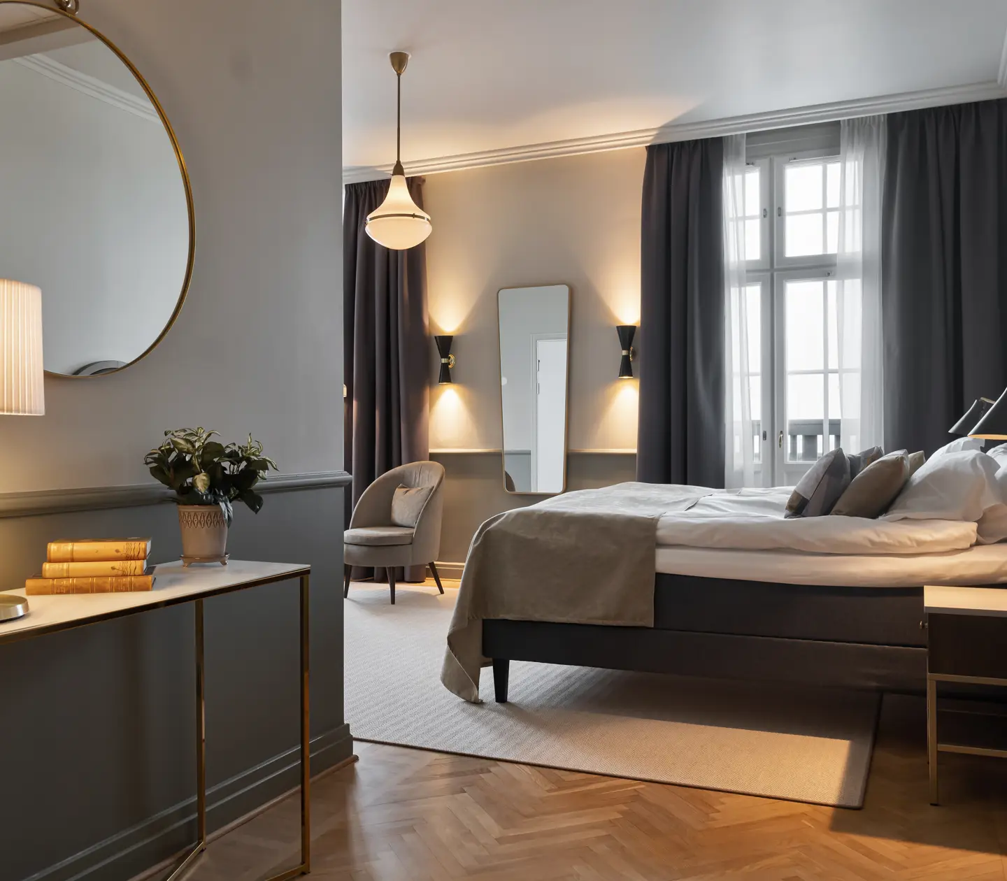 Mysigt hotellrum med dubbelsäng, fåtöljer, spegel och fönster