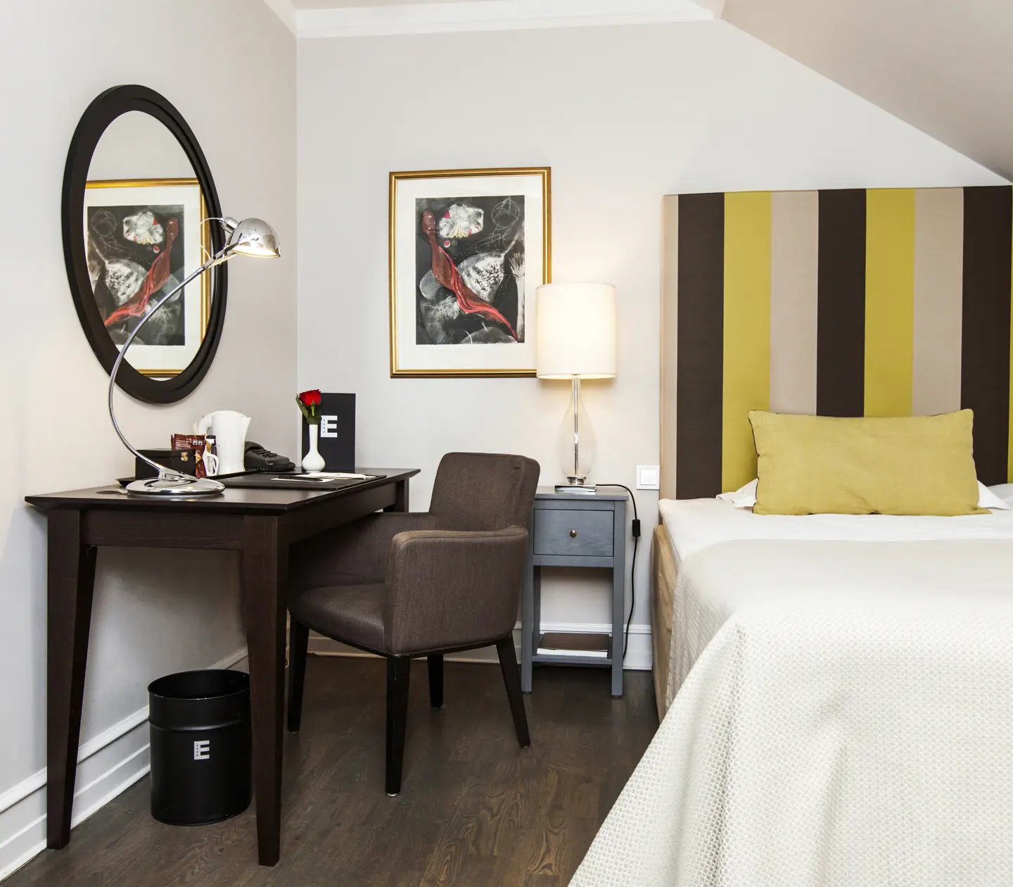 Hotellrum med enkelsäng, skrivbord och spegel