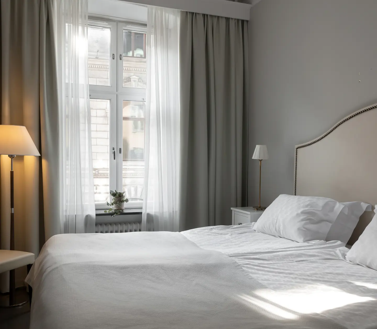 Mysigt hotellrum med dubbelsäng, golvlampa och fönster