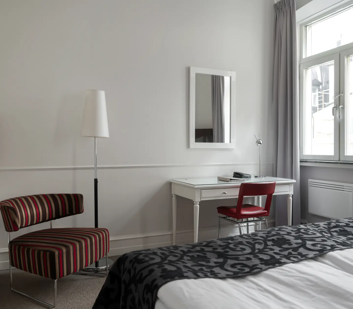 Hotellrum med skrivbord, fåtölj och spegel