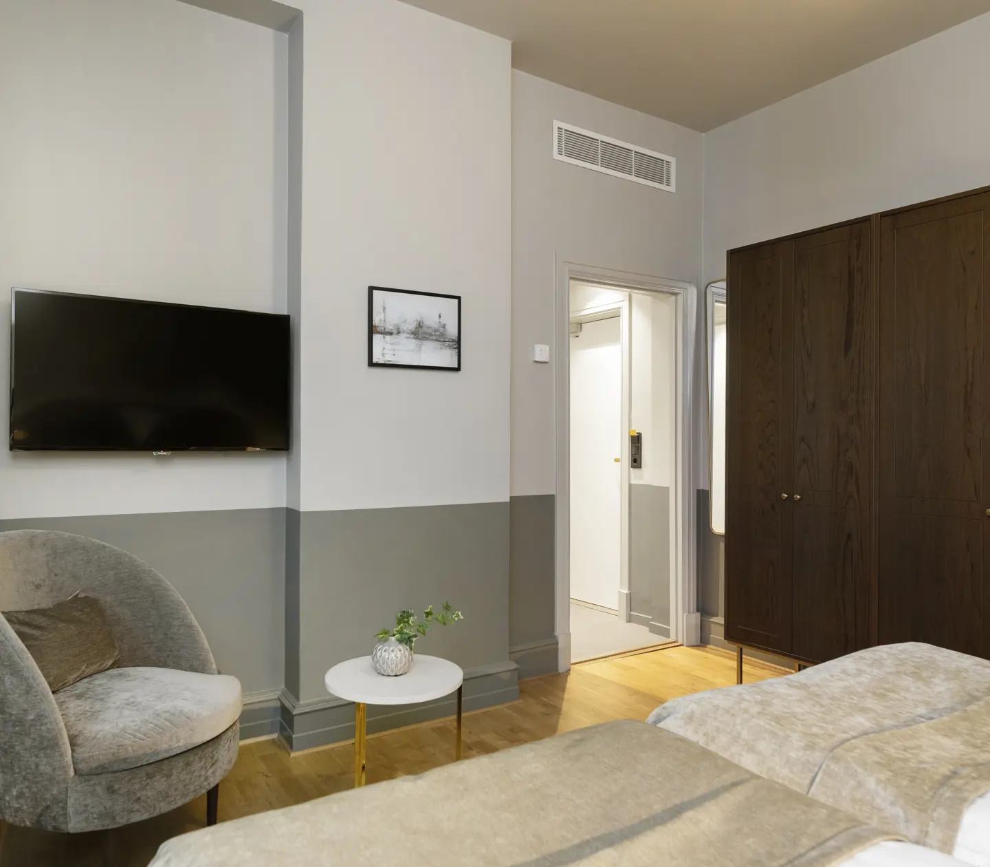Hotellrum med garderob, fåtölj och tv