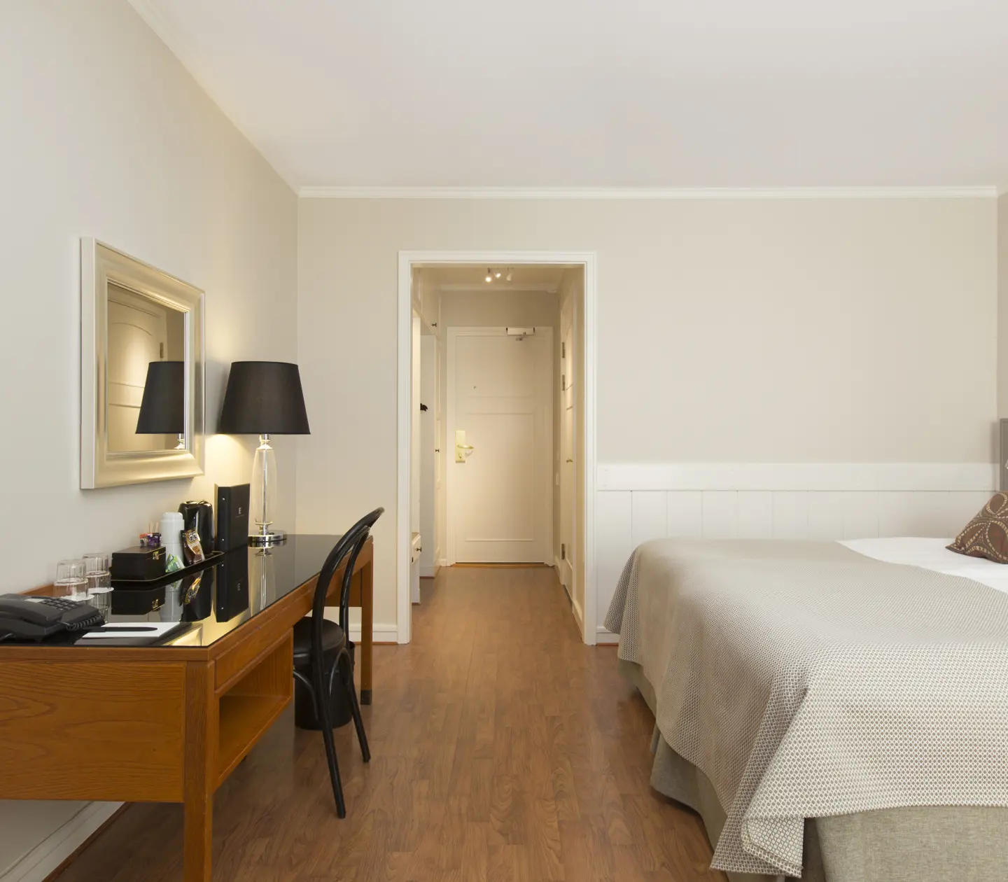 Hotellrum med dubbelsäng, skrivbord och spegel