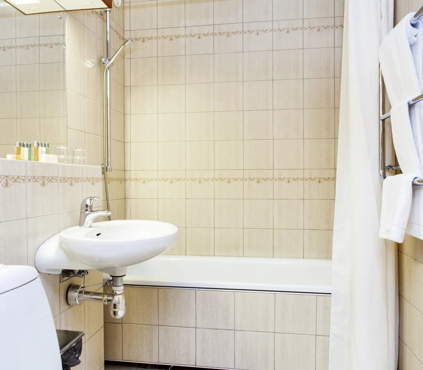 Beige badrum med badkar, handfat och handdukar