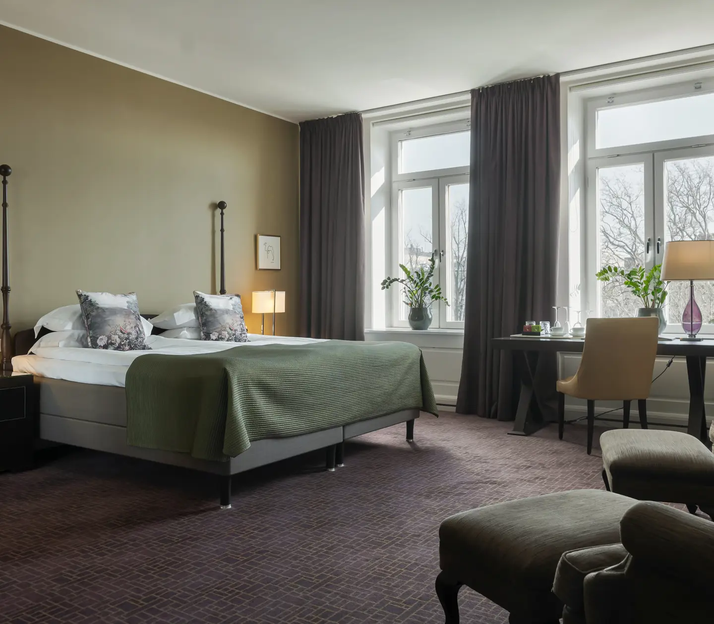 Hotellrum med stor säng, fåtöljer, skrivbord och fönster