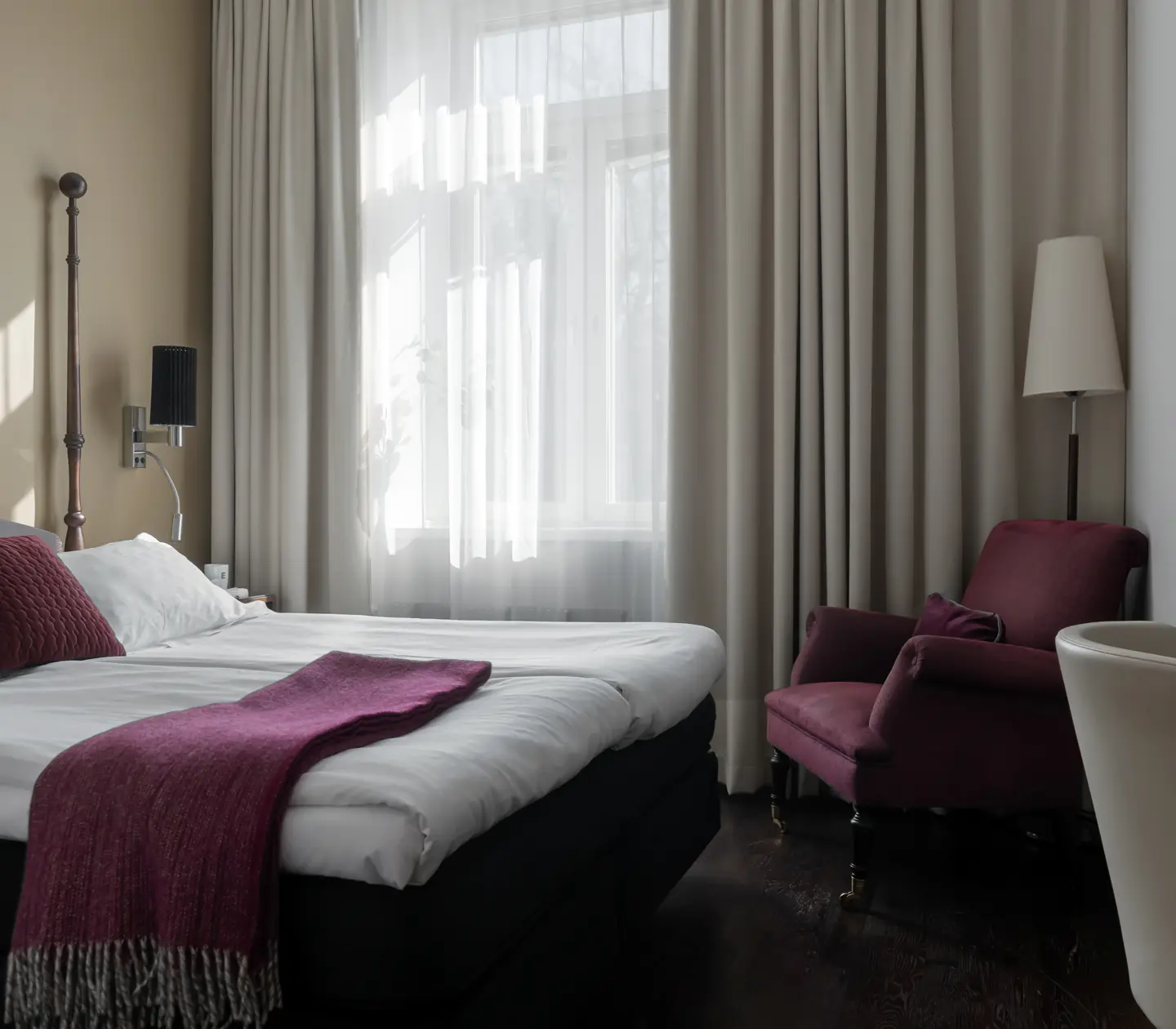 Ljust hotellrum med säng, fåtölj och fönster