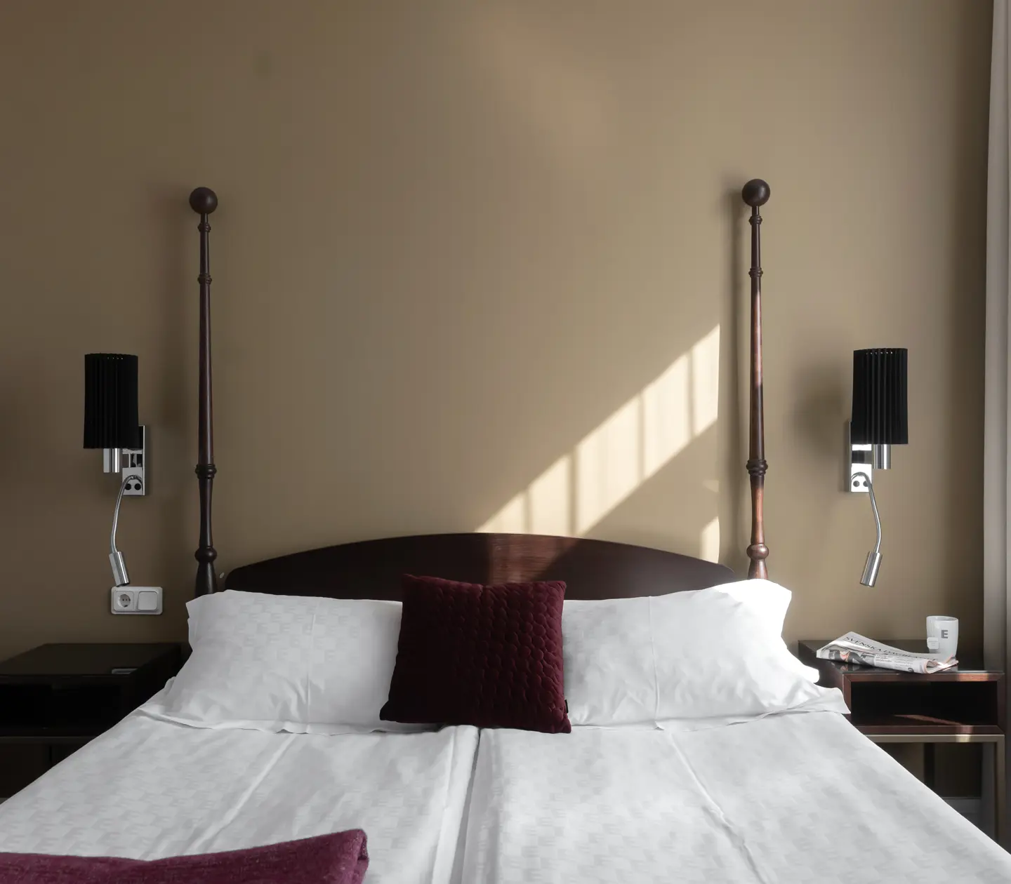Ljust hotellrum med säng, nattduksbord och sänglampor