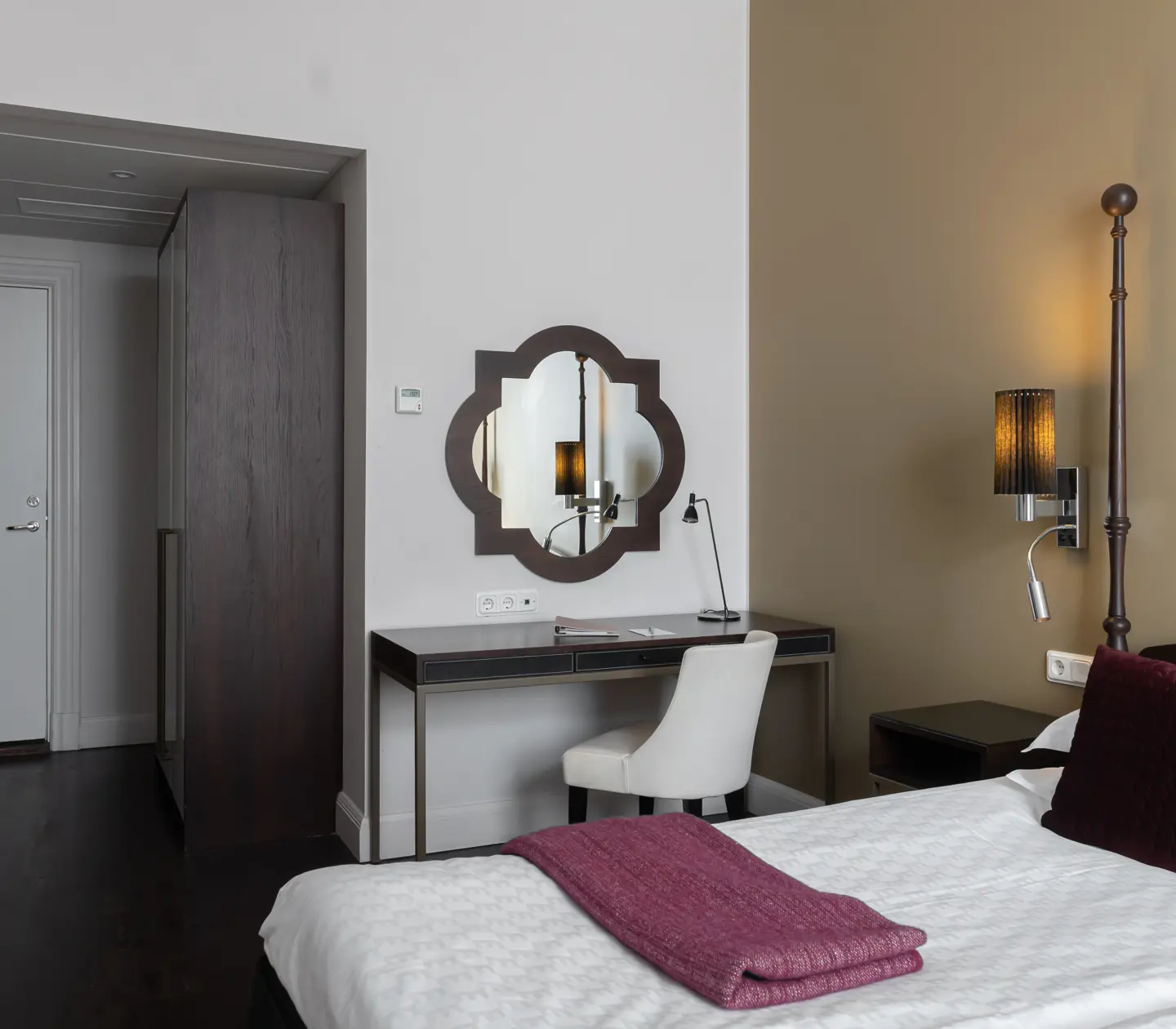Ljust hotellrum med skrivbord, spegel och säng